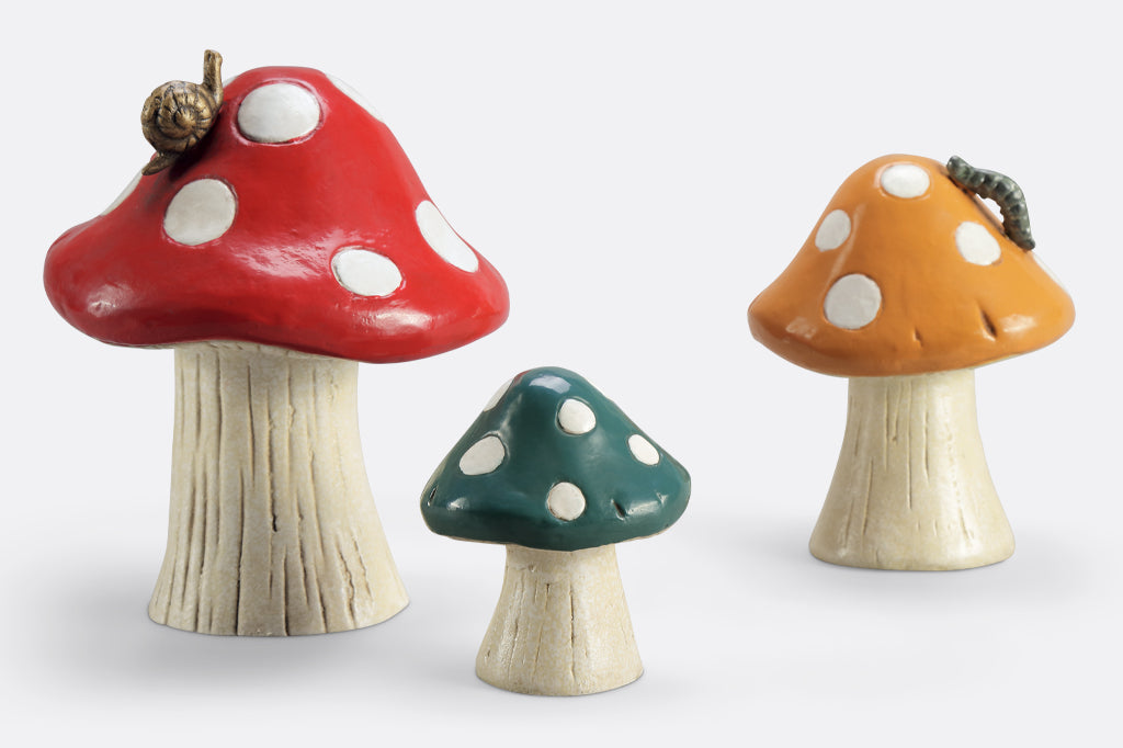 set of three mushroom garden sculpture. red mushroom speckled with white dots and a bronze snail on mushroom cap. Dark mustard colored mushroom with caterpillar on cap. forest green with hint of blue mushroom garden sculpture