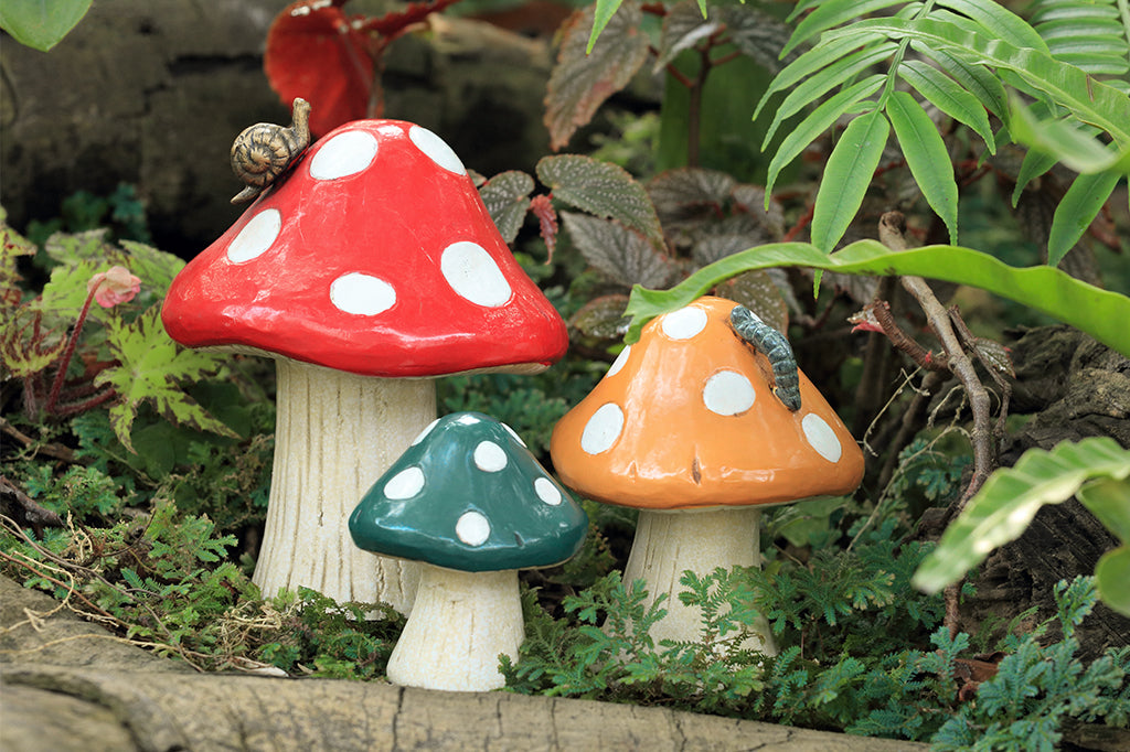Set of three cast metal garden sculpture with small snail and caterpillar details set in shade garden