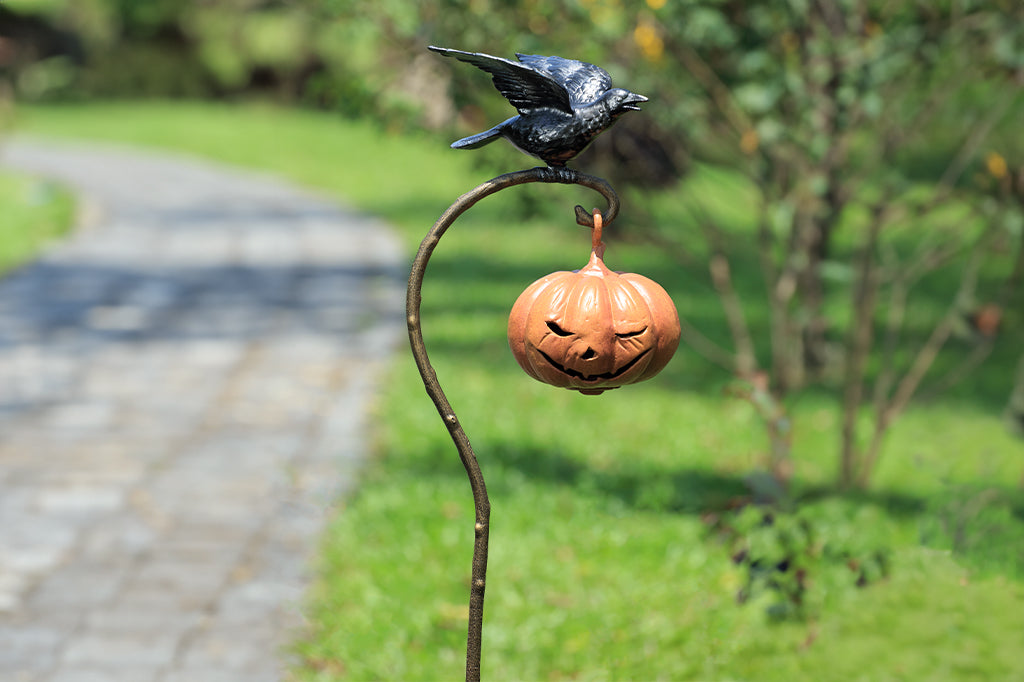 staked jack-o-lantern shaped outdoor lantern with black raven sat atop of branch detail