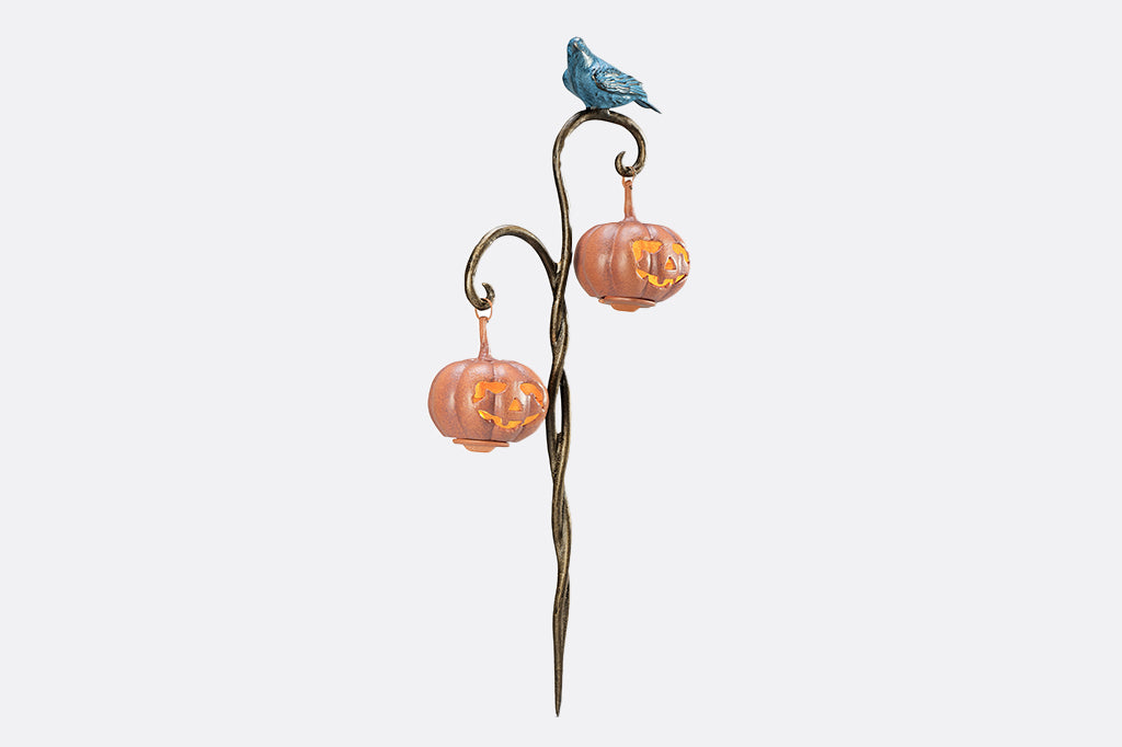 cast metal twisted branch lantern holding two jack o lantern lanterns with black blue raven sitting on branch