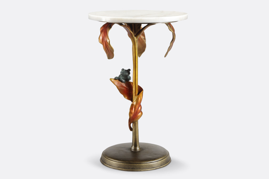 cast metal tropical drink table with white marble top in a coppery color featuring tropical leaves and a green frog balancing on a leaf