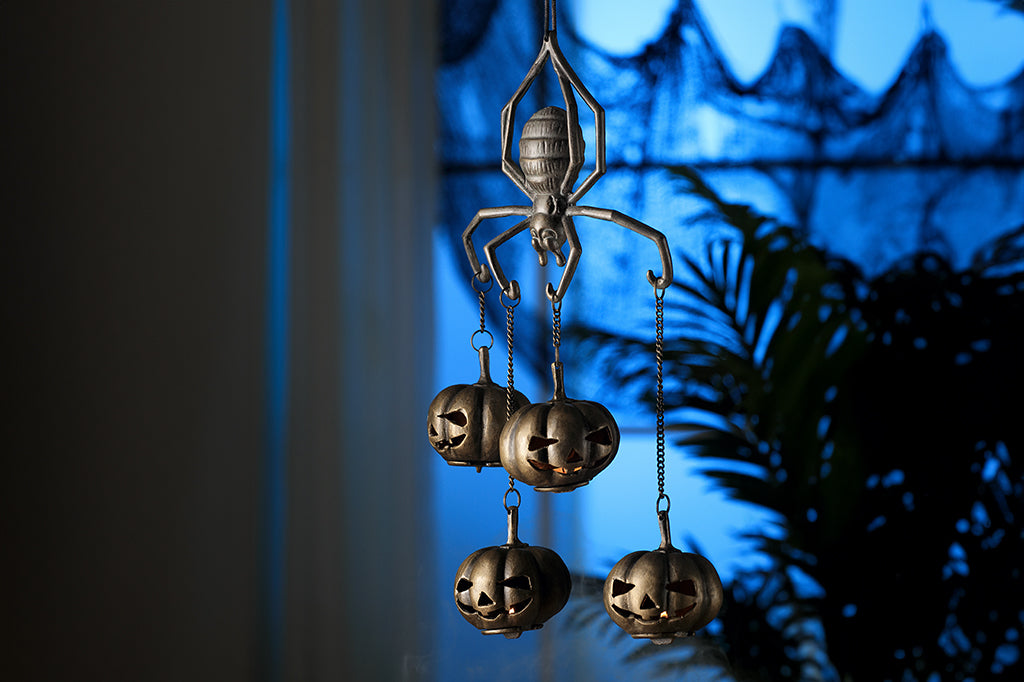 cast metal spider with four jack o lantern pumpkins suspended from spider arms