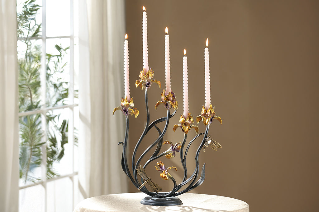cast metal iris taper candelabra holding five tapers, irises are a delicate blend of yellow with purple. Dragonfly detailing on stem of flowers set on table