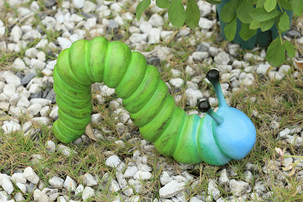 cast metal caterpillar with two antenna, colored in a lime green fading to a sky blue towards the head of caterpillar set in garden rock scene