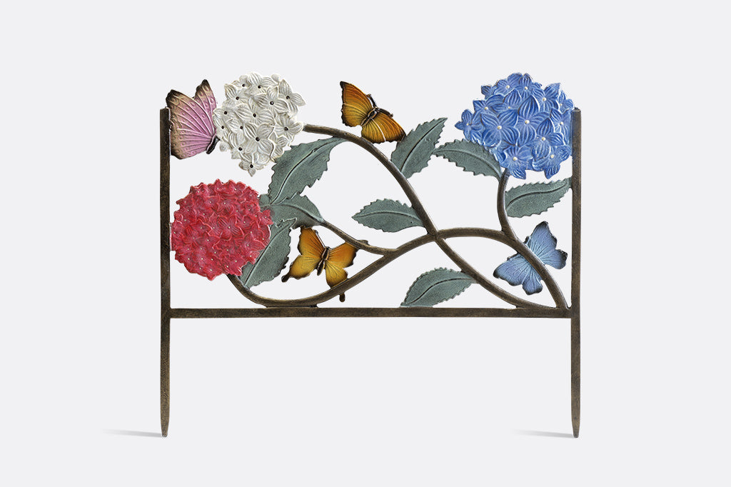 in a garden edging frame, 4 butterflies scatter amongst bold hydrangea blossoms of blue, white, and pink with green leaves