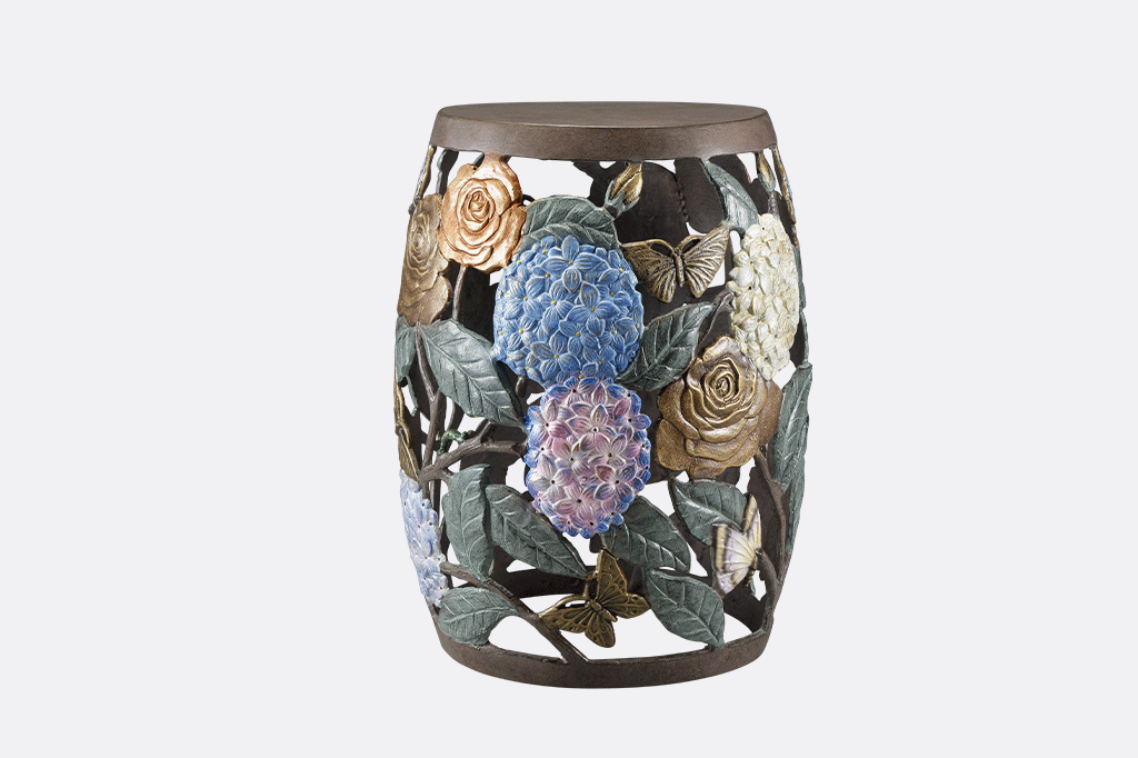 animation of 3 side views of garden accent stool. Cast metal garden stool features beautiful roses, butterflies, and the vibrant hues of hydrangeas.