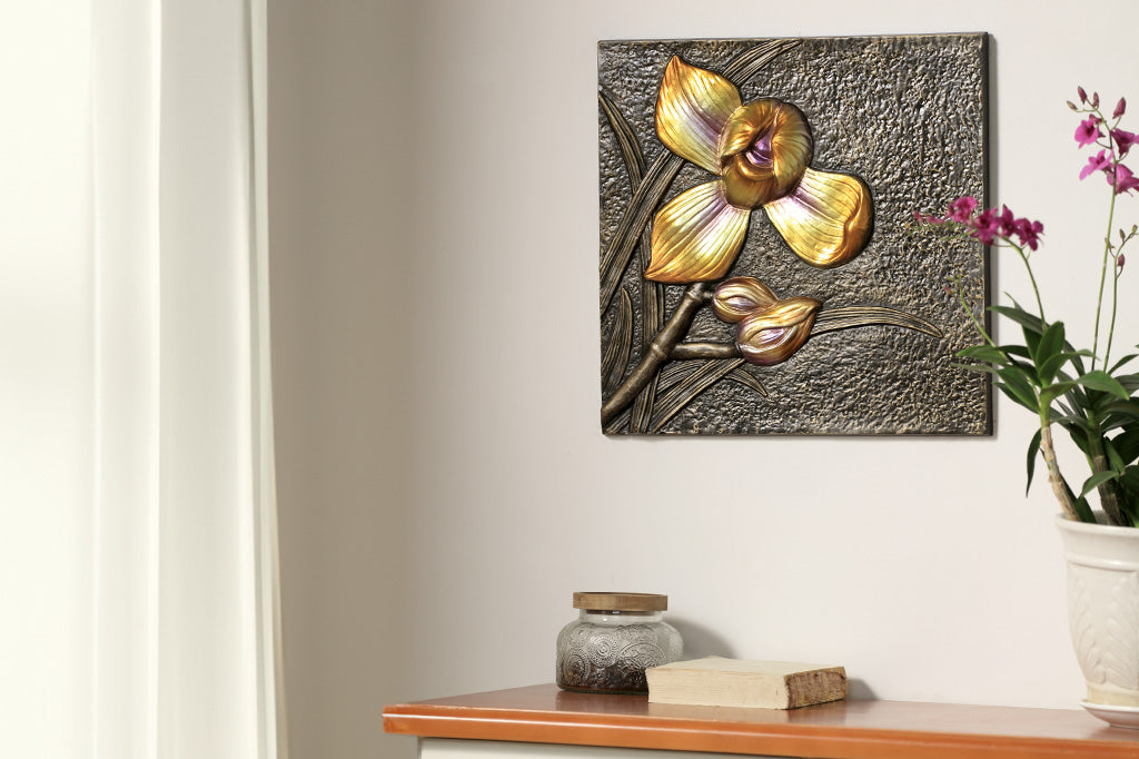 Wall plaque features metallic yellow orchid and bud, hung over dresser with decorative jar and potted orchid