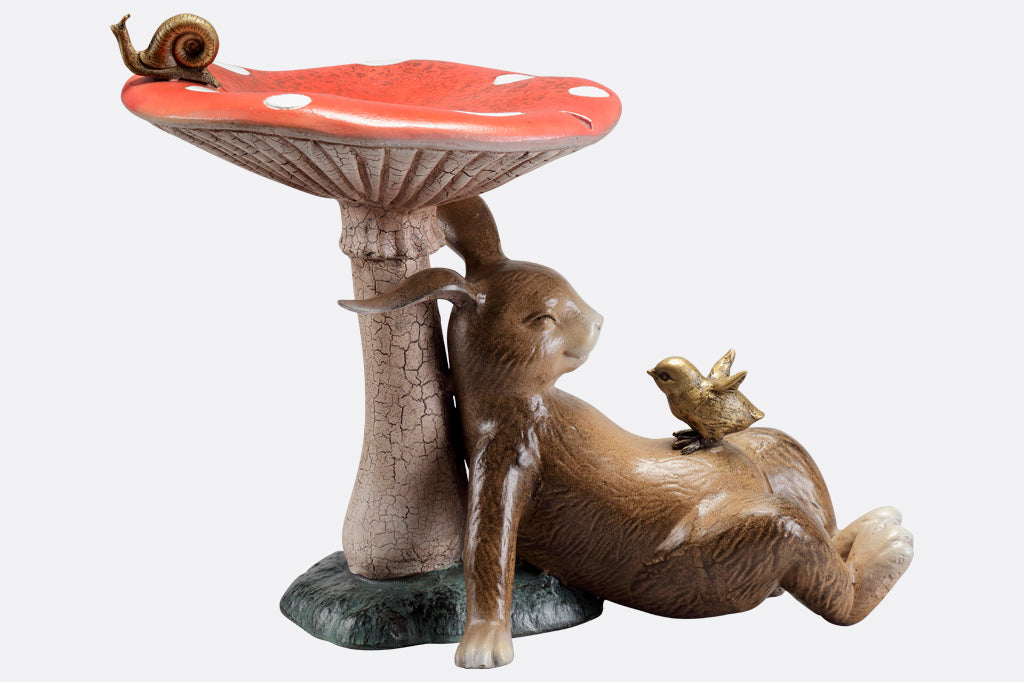 Bunny under a toadstool sculpture with chick and snail - mushroom is birdbath/birdfeeder