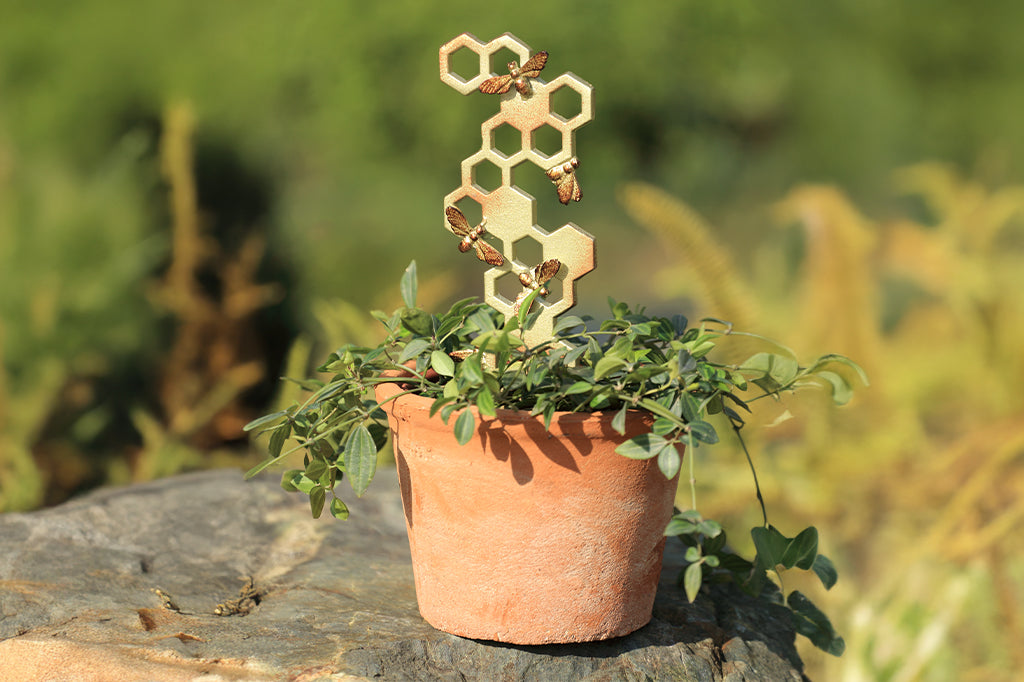 Cast metal beehive planter trellis in potted plant