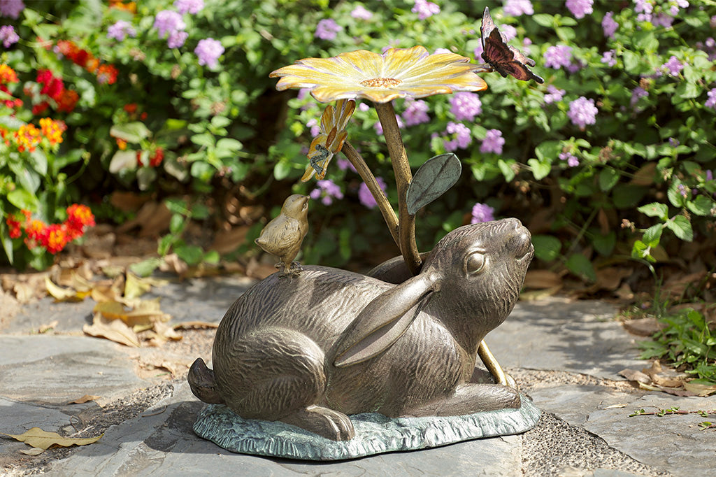 rabbit sculpture and birdbath/birdfeeder. A rabbit holds a blossom, surrounded by a chick, butterfly, and caterpillar