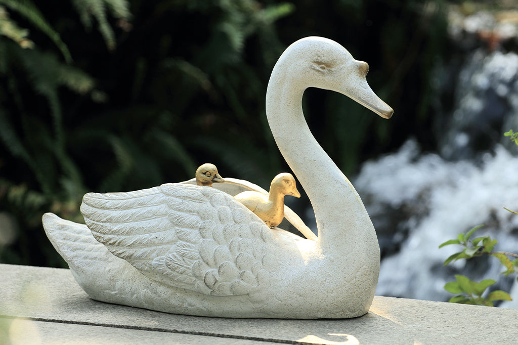 cast metal garden sculpture of mama swan with two baby cygnets nestled on her back