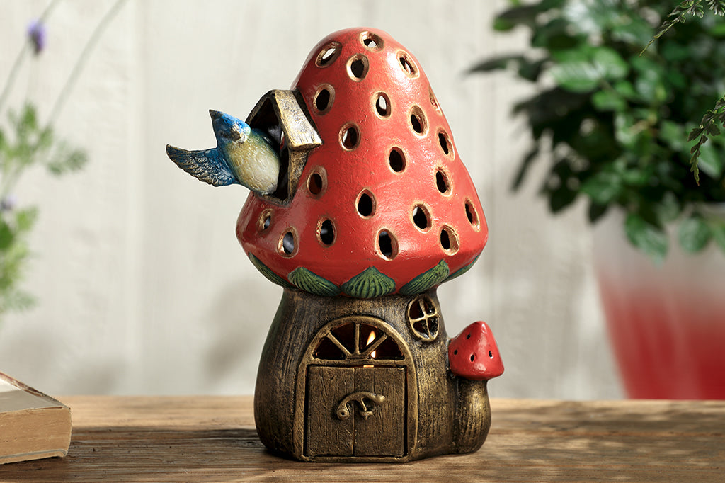 cast metal strawberry house lantern with blue jay waving out the side of the window