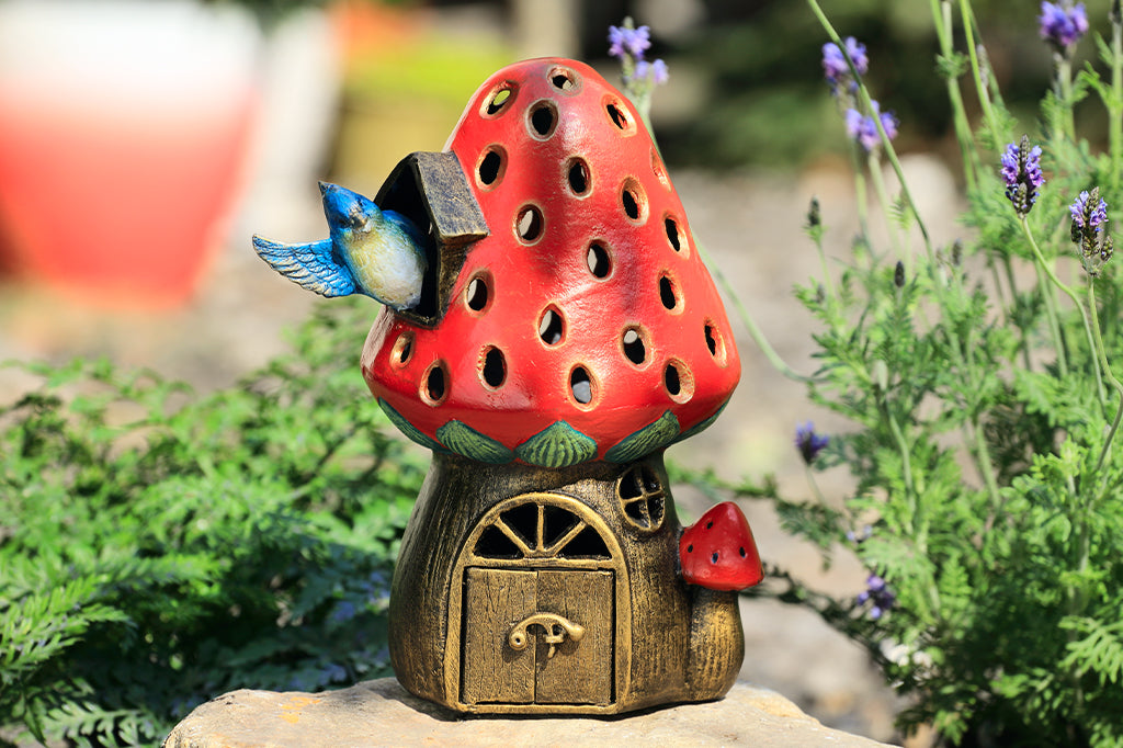 cast metal strawberry house lantern with blue jay waving out the side of the window