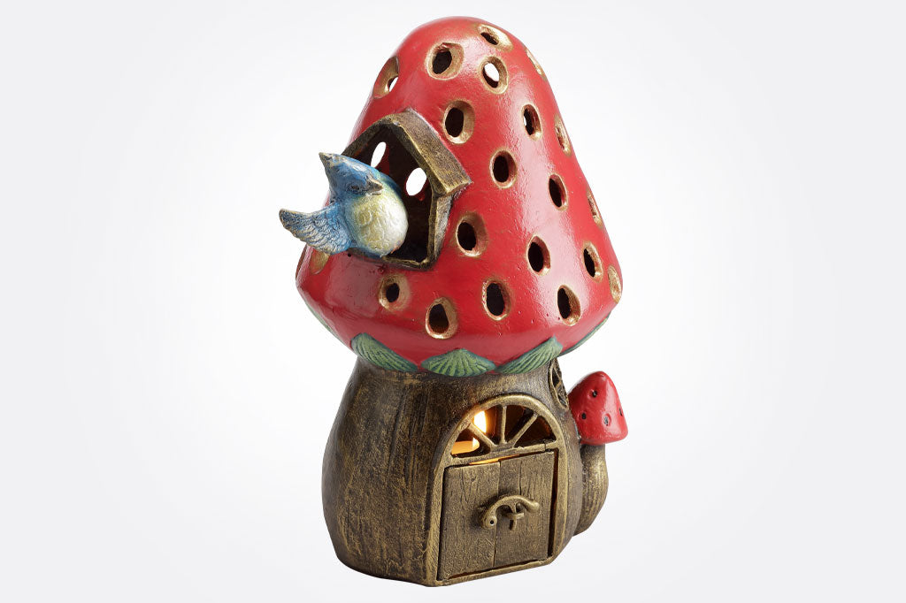 Decorative strawberry and mushroom-shaped candle lantern with a bluebird waving from window