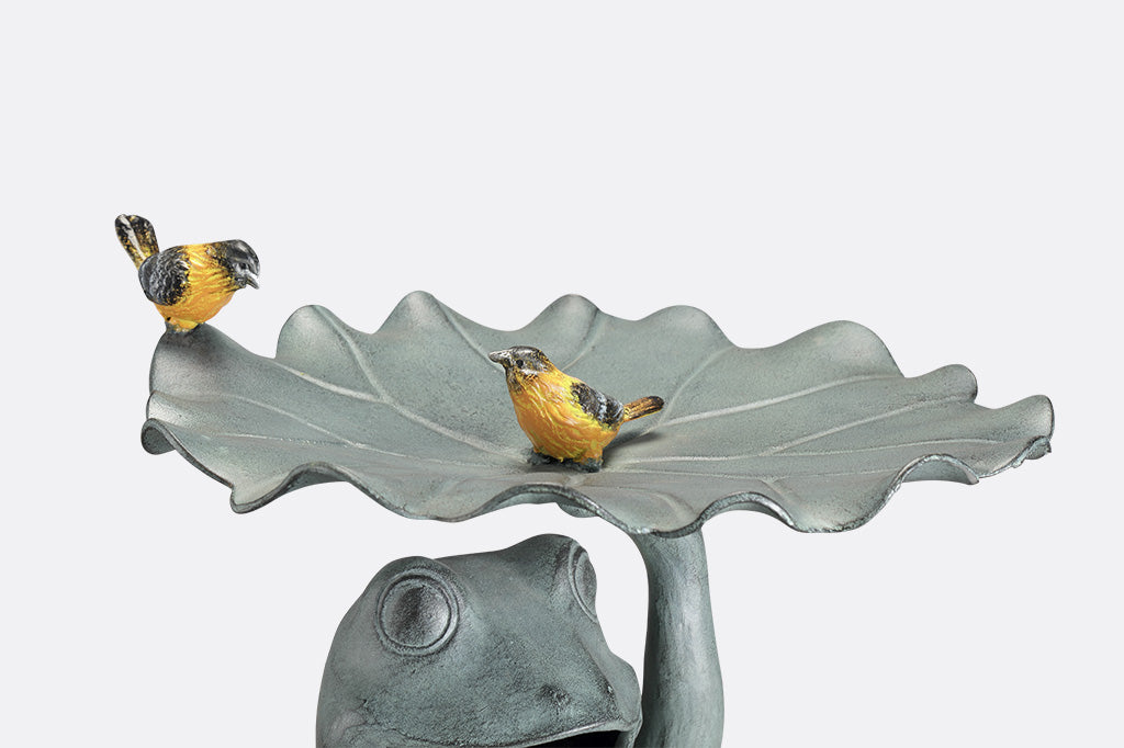 closeup view of Birdbath that features a Frog holding a sunflower with yellow songbird accents on a lilypad basin.