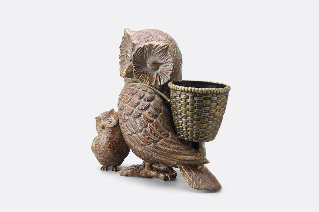 Decorative owl sculpture with a basket on a white background