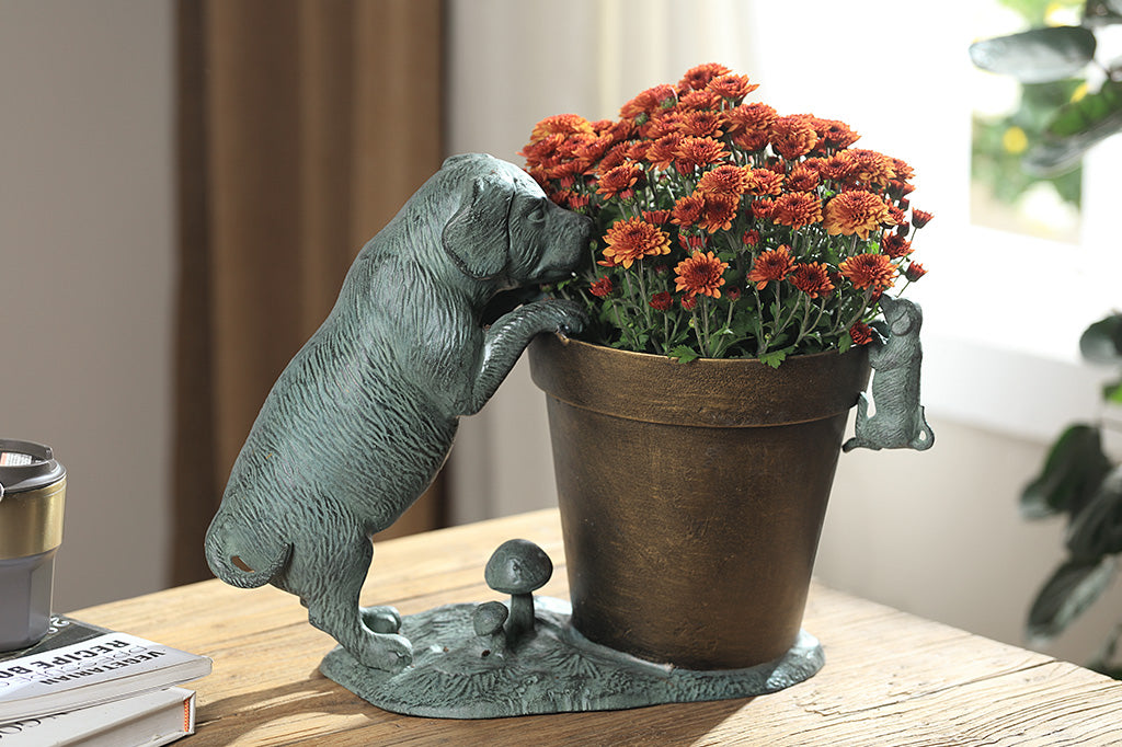A planter statue with a small puppy holding onto the lip of the pot while a bigger dog peers over.