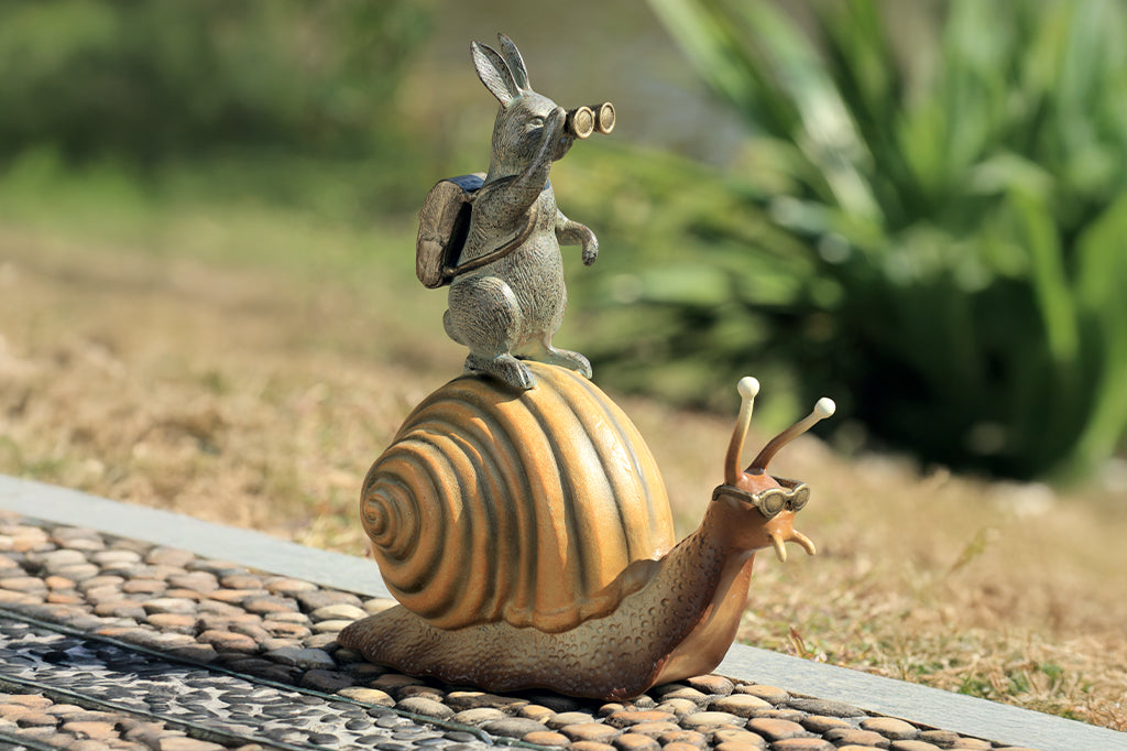 cast metal garden sculpture adventuring rabbit with binoculars riding on a snail with sunglasses