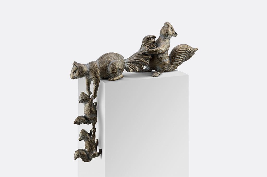 A sculpture of 4 squirrels lifting themselves up a corner.