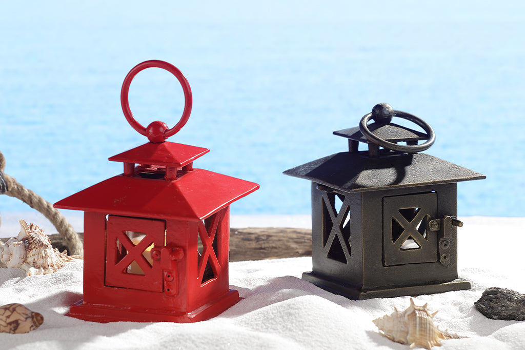 cast metal small lanterns in red and bronze set on sandy set with seashells #color_red #color_bronze