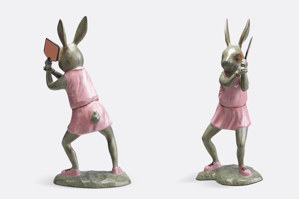 Rabbit garden sculpture with pickleball theme. She wears a pink dress, pink sneakers and holds a pink pickleball paddle - alternate view of back and side