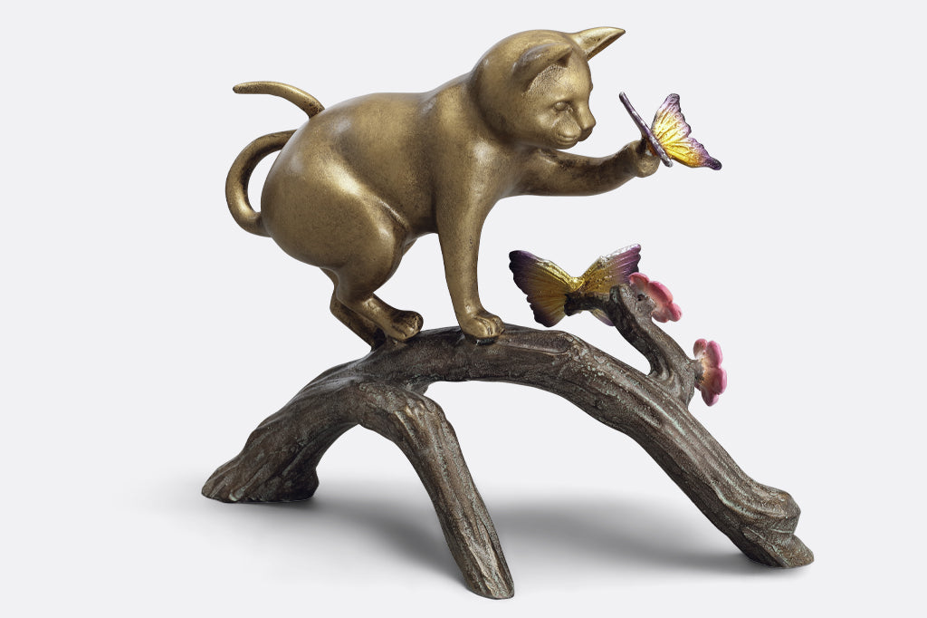 cast aluminum cat playing with butterfly on log with flowers