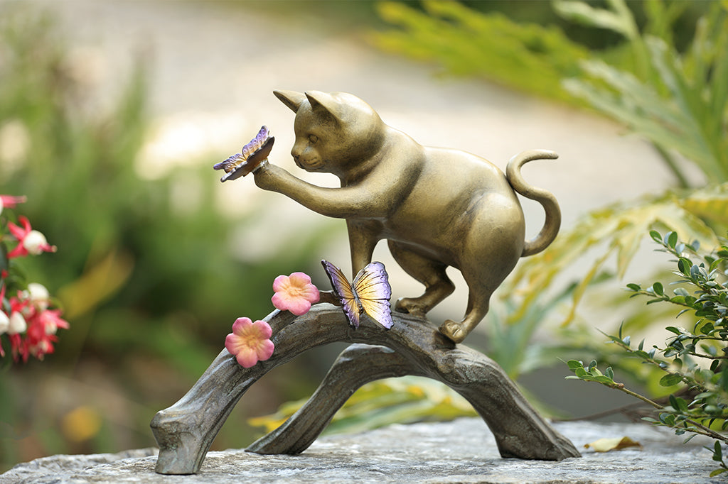 cast aluminum cat playing with butterfly on log with flowers
