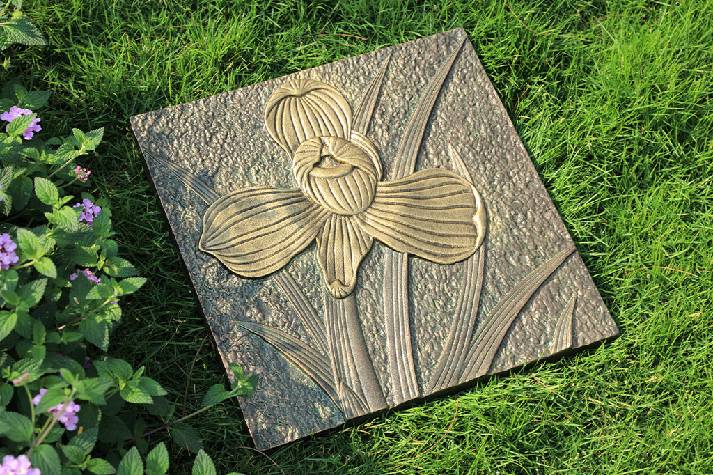 cast metal orchid stepping stone, flower design is raised slightly. Set on garden grass