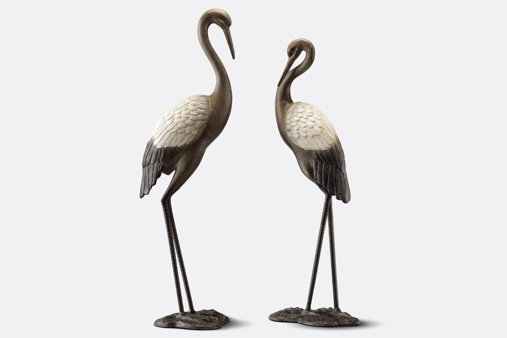 cast metal garden crane pair, white wings with dark bodies elegant and poised