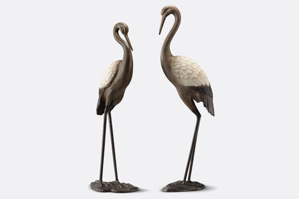 cast metal garden crane pair, white wings with dark bodies elegant and poised