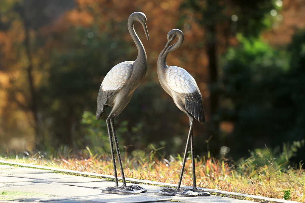 cast metal crane pair set in garden space autumn colors