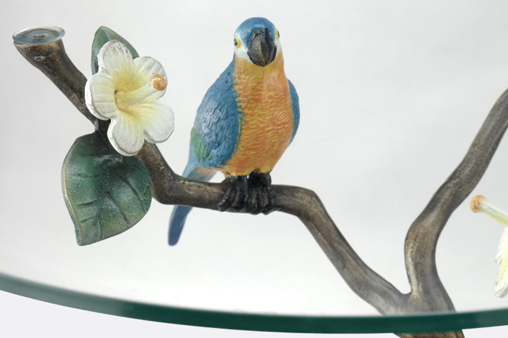 detailed view of blue and yellow parrot perched on branch next to white hibiscus bloom