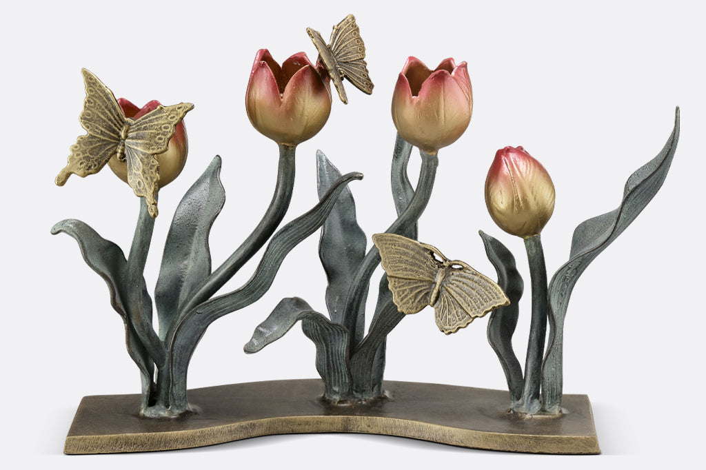 cast metal tulip taper candleholder, tulips are a gradient of pink to yellow. group of three butterflies on petals and foliage