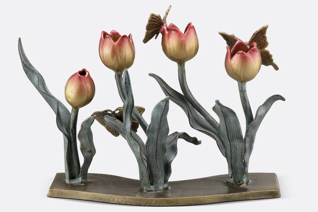 cast metal tulip taper candleholder, tulips are a gradient of pink to yellow. group of three butterflies on petals and foliage