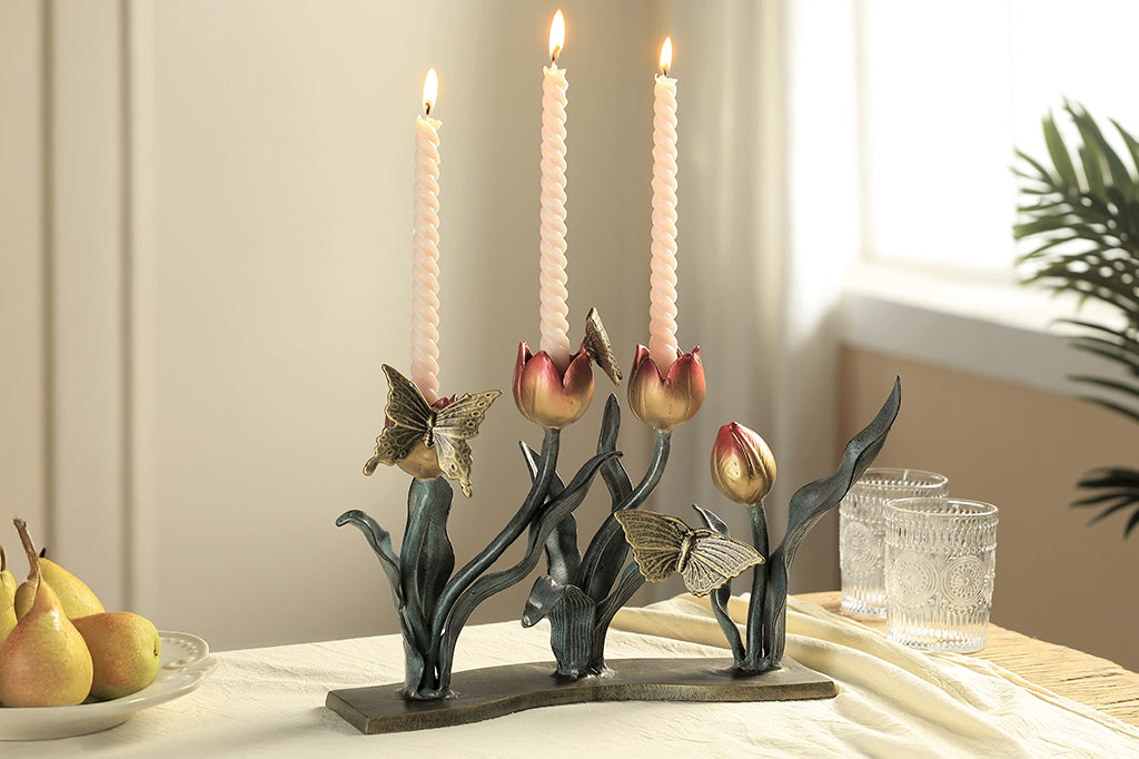 cast metal tulip taper candleholder, tulips are a gradient of pink to yellow. group of three butterflies on petals and foliage