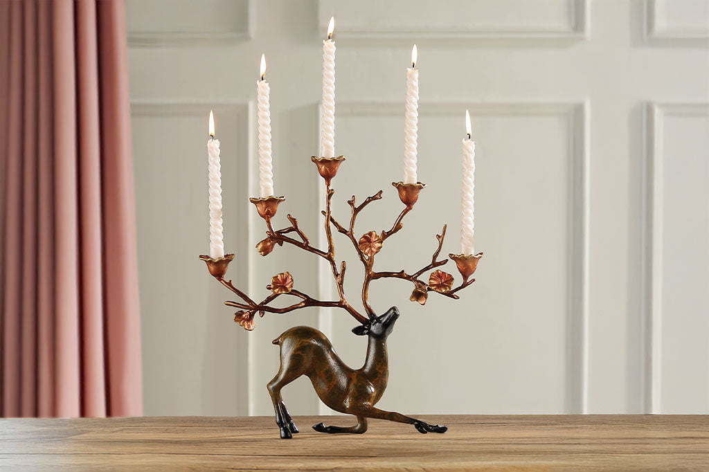 Decorative taper candle holder with deer design - antlers are blooming branches - on a wooden surface
