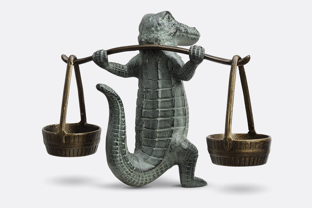 A sculpture of an alligator holding up two buckets.