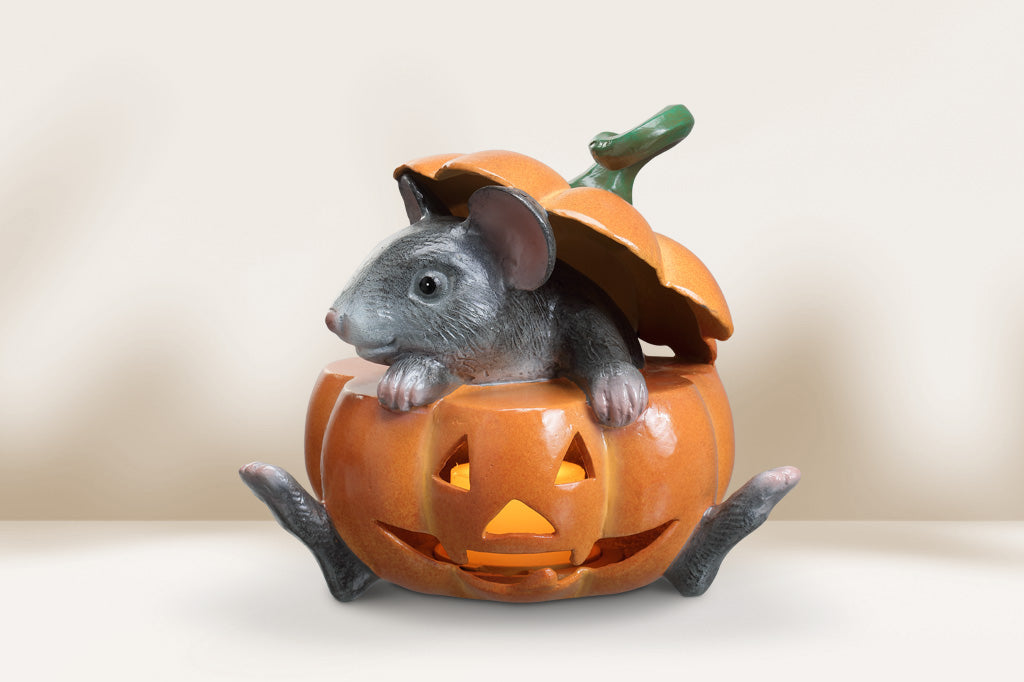 Decorative pumpkin candle lantern with a mouse inside on a neutral background