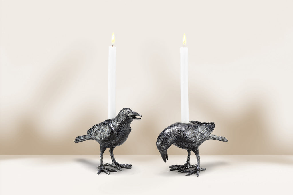 Two bird-shaped candle holders with lit candles on a neutral background