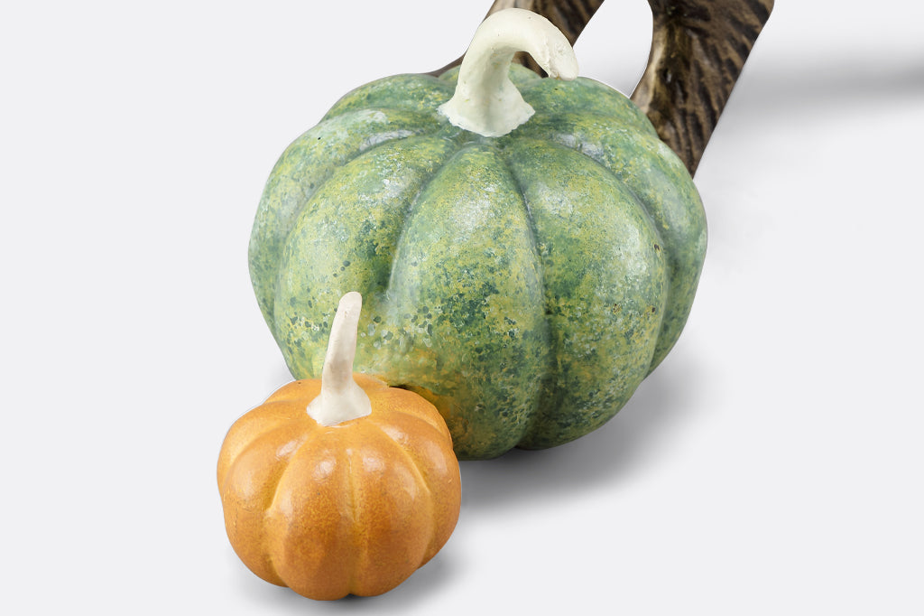 close up of pumpkins, one light orange and one larger green pumpkin with dark green and orange specking