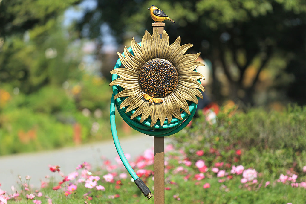 A garden stake hose holder with a sculpture of a sunflower and bird.