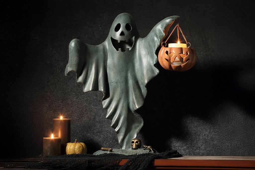 cast metal smiling ghost holding jack o lantern with candle inside