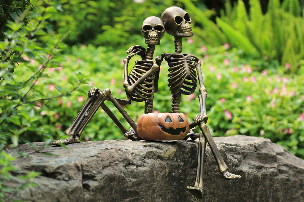 cast metal skeleton couple with jack o lantern set in garden