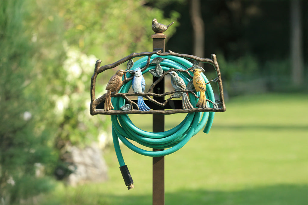 Decorative garden hose holder with bird design against a blurred green outdoor background