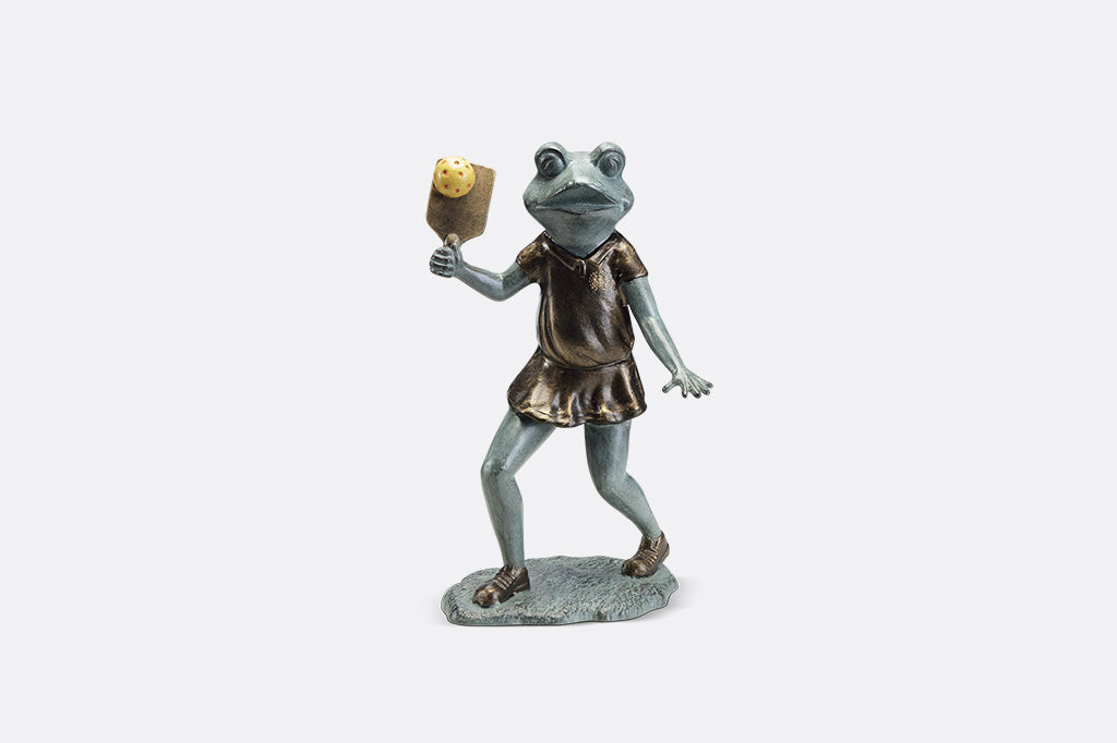 Sculpture of a frog holding a paddle playing pickleball.