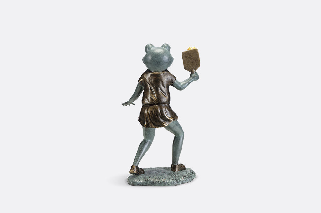 Sculpture of a frog holding a paddle playing pickleball.