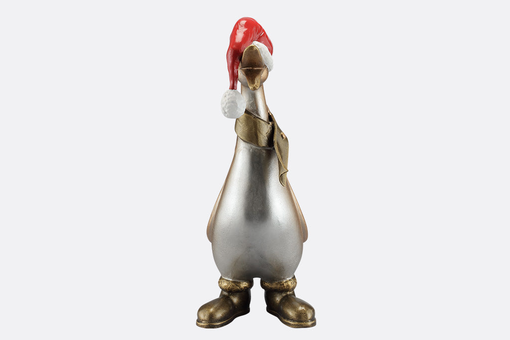 The front of a statue of a duck wearing a scarf, boots, and oversized santa hat covering his eyes.