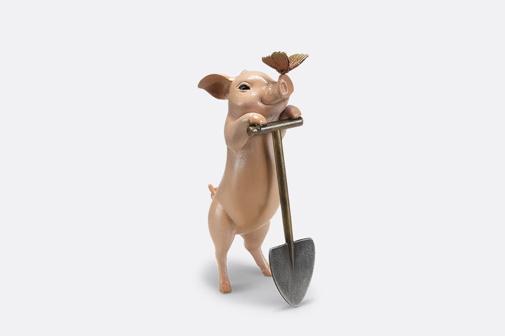A sculpture of a pig holding a shovel with a butterfly landing on it's nose.