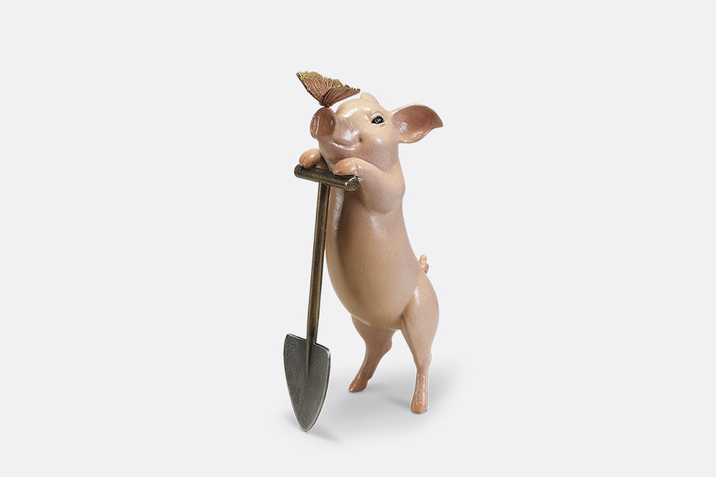 A sculpture of a pig holding a shovel with a butterfly landing on it's nose.