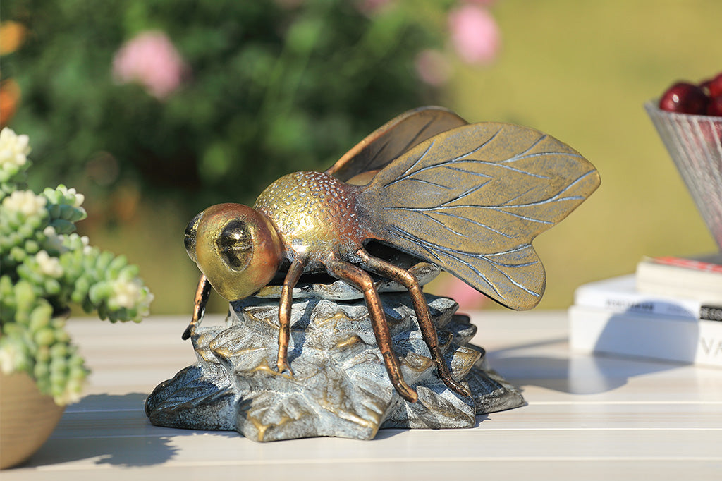 A statue of a bee landing on a flower.